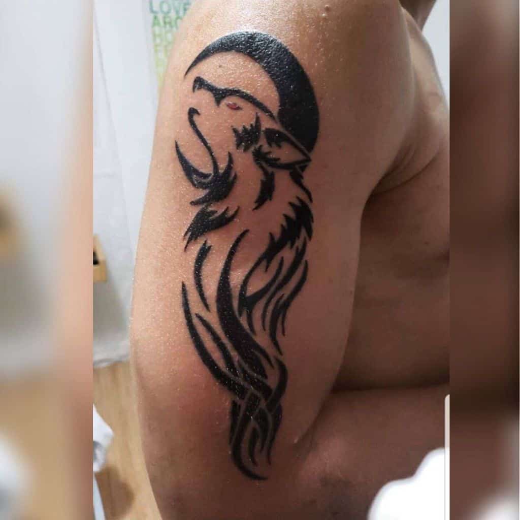 Tattoo of a howling wolf with a crescent moon on an upper arm