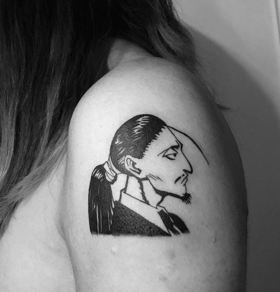 Bold black-ink tattoo of Silva Zoldyck from Hunter x Hunter, featuring his sharp profile and iconic ponytail on the upper arm