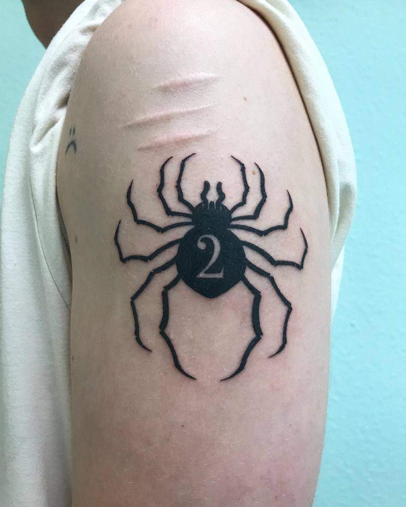 Bold black tattoo of the Phantom Troupe spider emblem from Hunter x Hunter, featuring the number 2 on the upper arm
