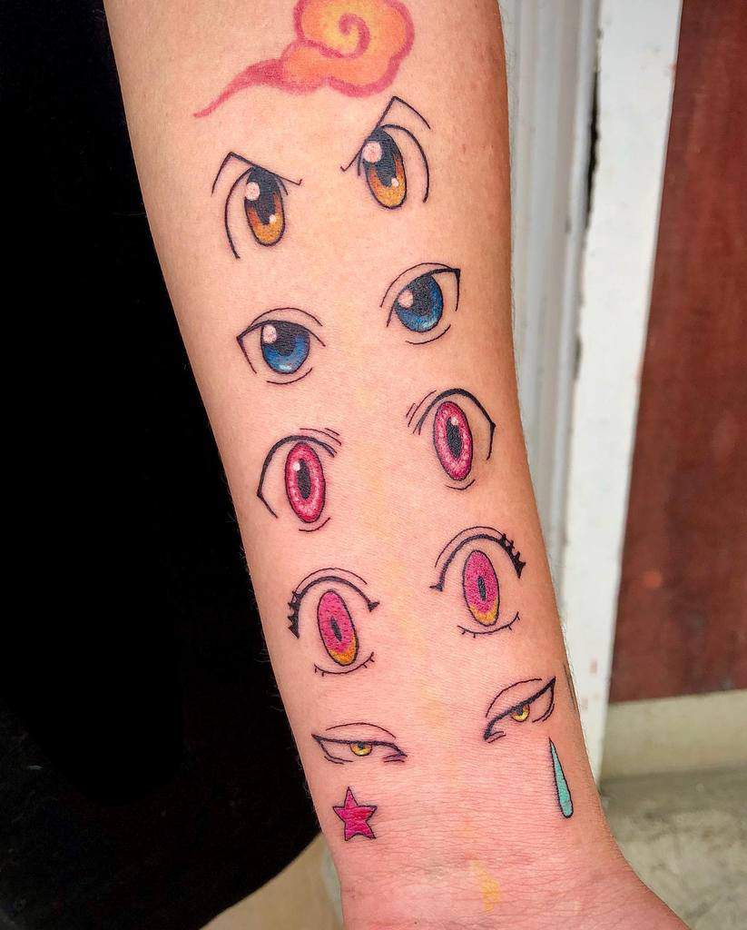 Colorful forearm tattoo featuring iconic Hunter x Hunter character eyes, including Gon's, Killua's, Hisoka's, and Kurapika's signature designs