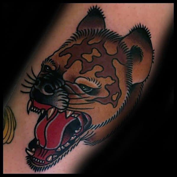 Traditional-style hyena tattoo with bold black outlines, deep red mouth, and stylized fur patterns, capturing a fierce snarling expression.