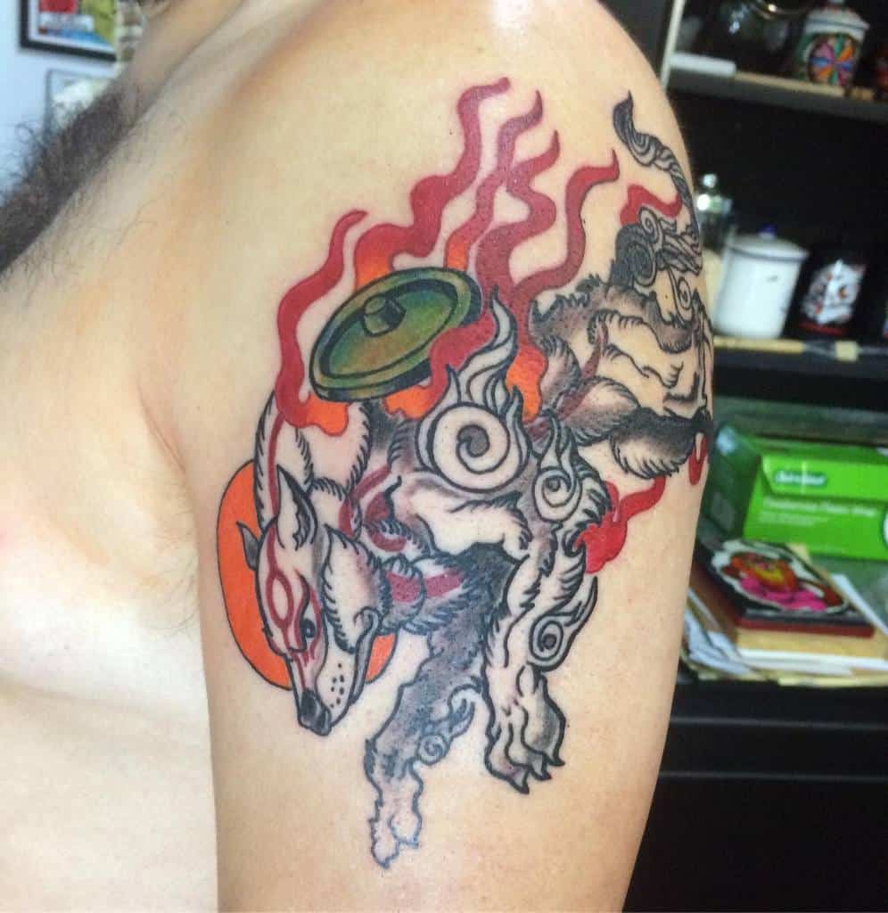 Japanese-inspired tattoo of a mystical wolf with vibrant flames and a shield design on a person's upper arm