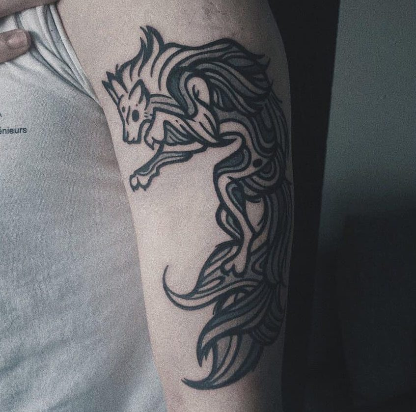 A tattoo of a stylized, flowing wolf design with subtle Japanese influences graces an upper arm