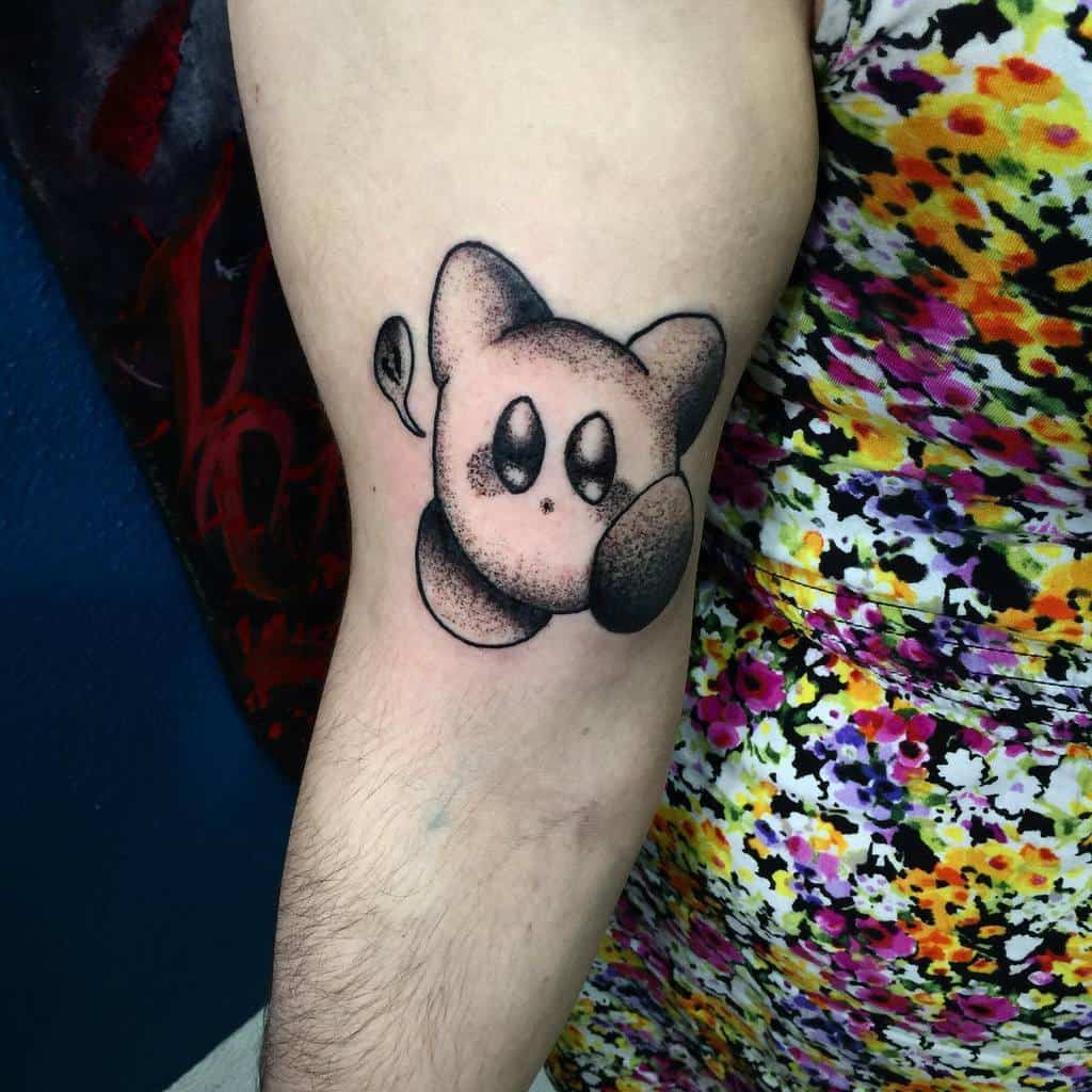 Black and grey Kirby tattoo with a stippled shading effect, a minimalist yet detailed design capturing Kirby’s classic puffed pose