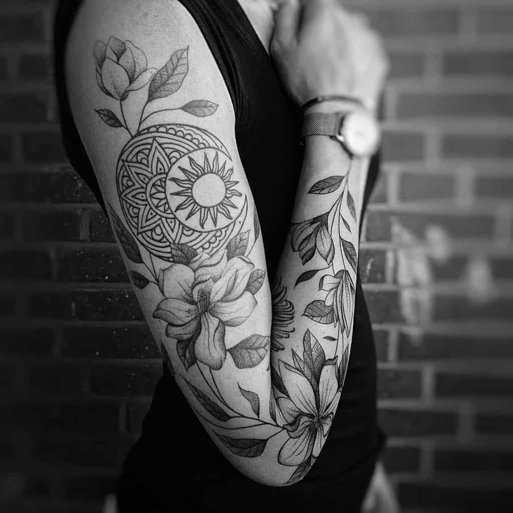 A stunning arm tattoo featuring magnolia flowers intertwines with a radiant sun design, all intricately crafted in black ink