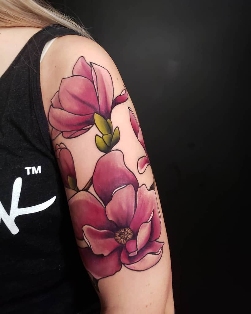A stunning arm tattoo features large pink magnolias with vibrant green stems