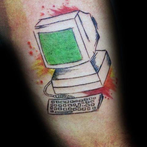 Colorful tattoo of a vintage desktop computer with a green screen and keyboard, accented by red and yellow splashes.