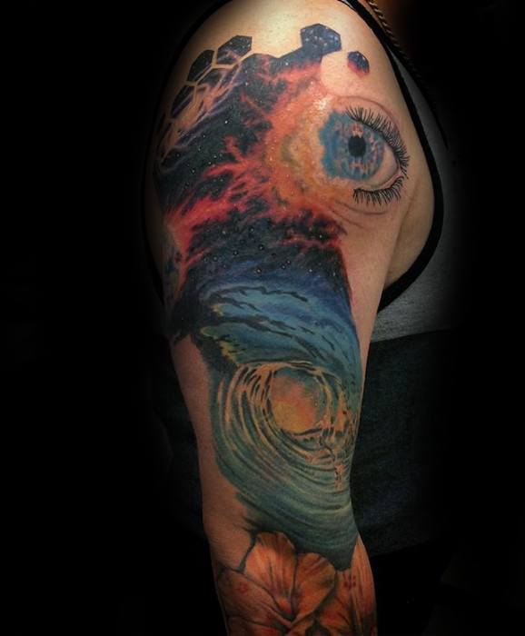 Colorful arm tattoo featuring an eye, cosmic scene, nebula, hexagonal patterns, and a flower