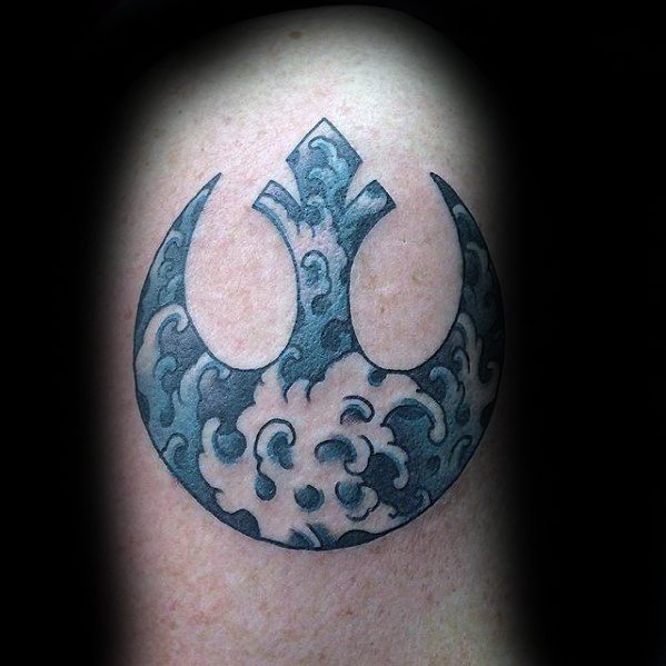 Black and gray Rebel Alliance tattoo with swirling cloud patterns, located on the upper arm.