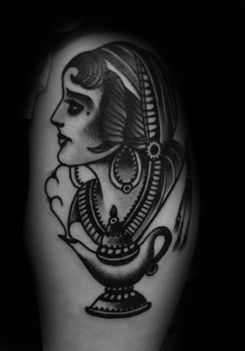 Tattoo of a woman's face with traditional jewelry and a genie lamp beneath her
