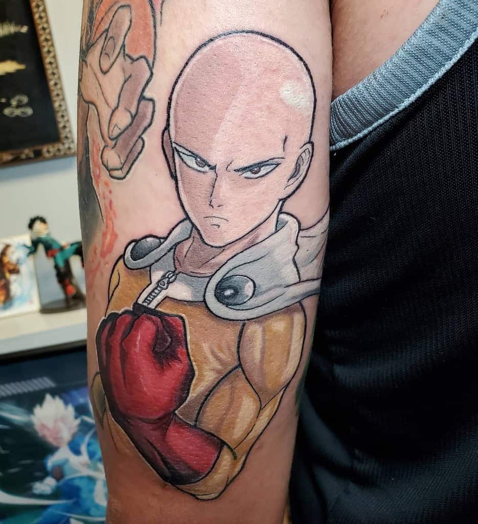 A detailed tattoo of Saitama from One Punch Man on a person's arm, featuring his signature yellow suit and red gloves
