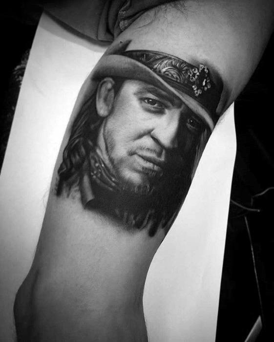 Black and white tattoo of Stevie Ray Vaughan, featuring his iconic hat and expressive facial details