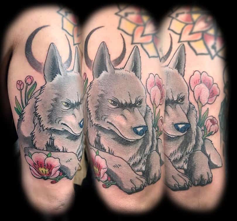 A striking tattoo of a fierce wolf with sharp features, surrounded by delicate flowers. The wolf exudes strength, while the soft colors of the flowers contrast beautifully with its intense gaze.