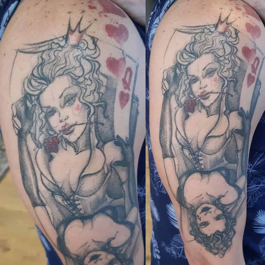 Tattoo of a playing card queen with a rose and decorative elements on a person's arm