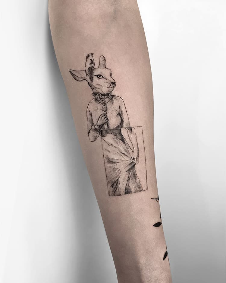 Intricate tattoo of a rabbit dressed in a vintage-style outfit, with fine detailing in black and gray, positioned inside a rectangular frame