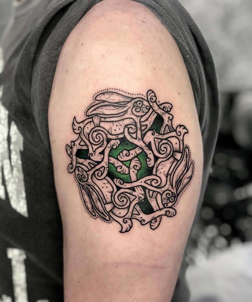 Detailed black and green tattoo of a rabbit surrounded by flowing, swirling lines and patterns, creating an abstract, organic design