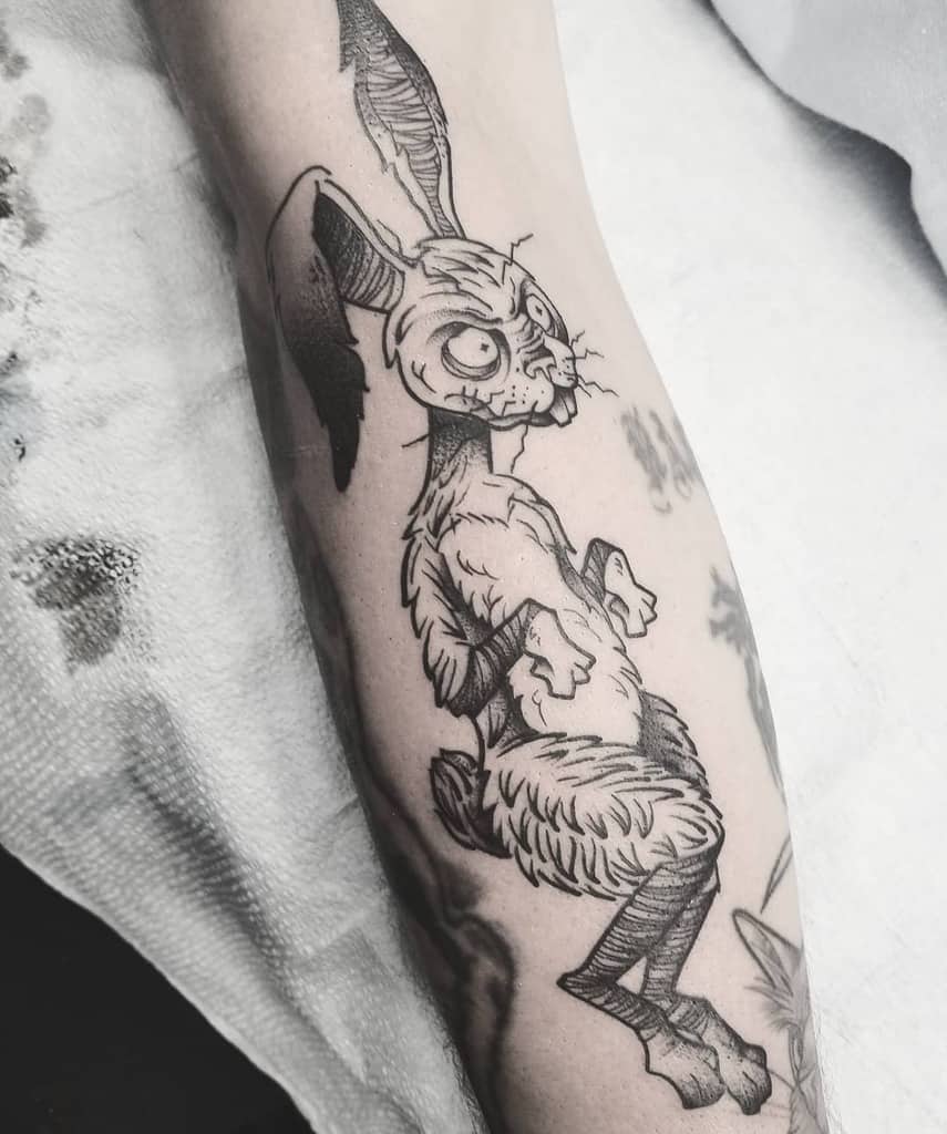 Forearm tattoo of an abstract rabbit with large eyes and long ears, displayed in black ink