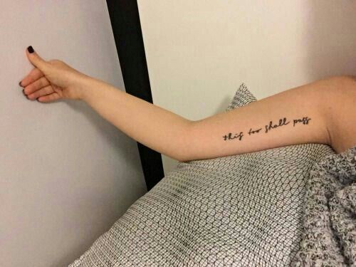 "This too shall pass" tattoo in cursive on the forearm.