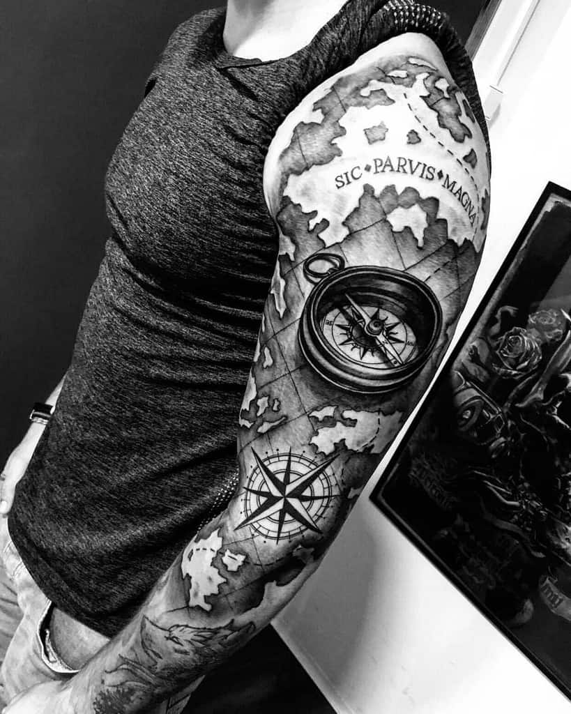 Black and white arm tattoo featuring a compass, map design, and the phrase "SIC PARVIS MAGNA"