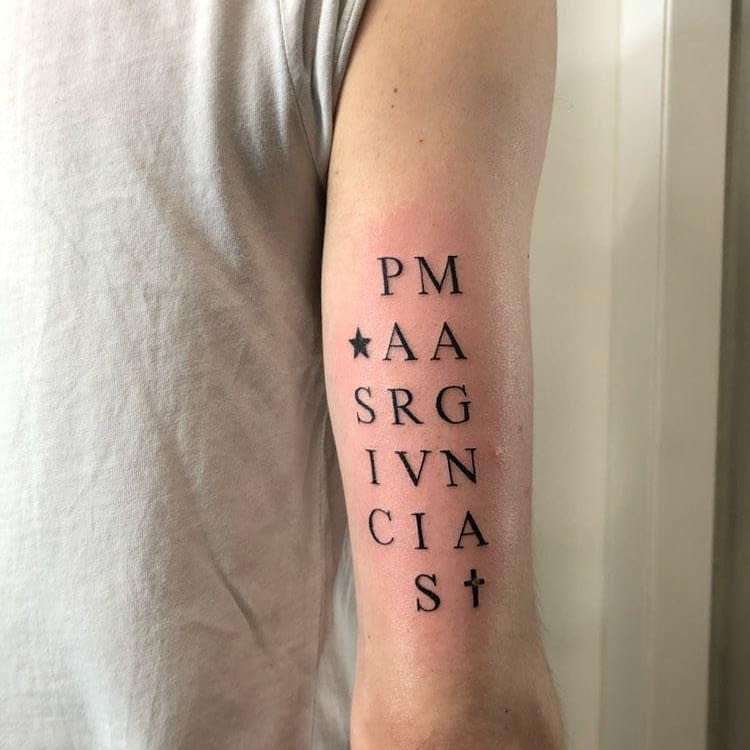 Arm tattoo with vertical lettering, star and cross symbols, creating a clean and minimalist black text design