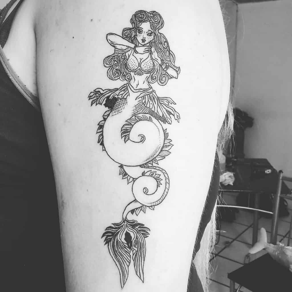 Black and white tattoo of a siren with long hair on an arm