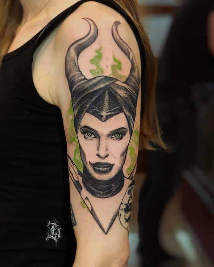 Detailed arm tattoo featuring Maleficent with striking green eyes and magical accents, showcasing a bold and powerful design