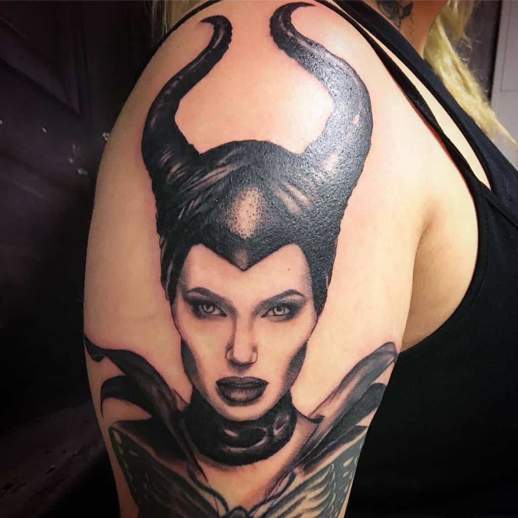 Realistic Maleficent tattoo on the upper arm, featuring bold blackwork and intense shading for a striking, lifelike effect