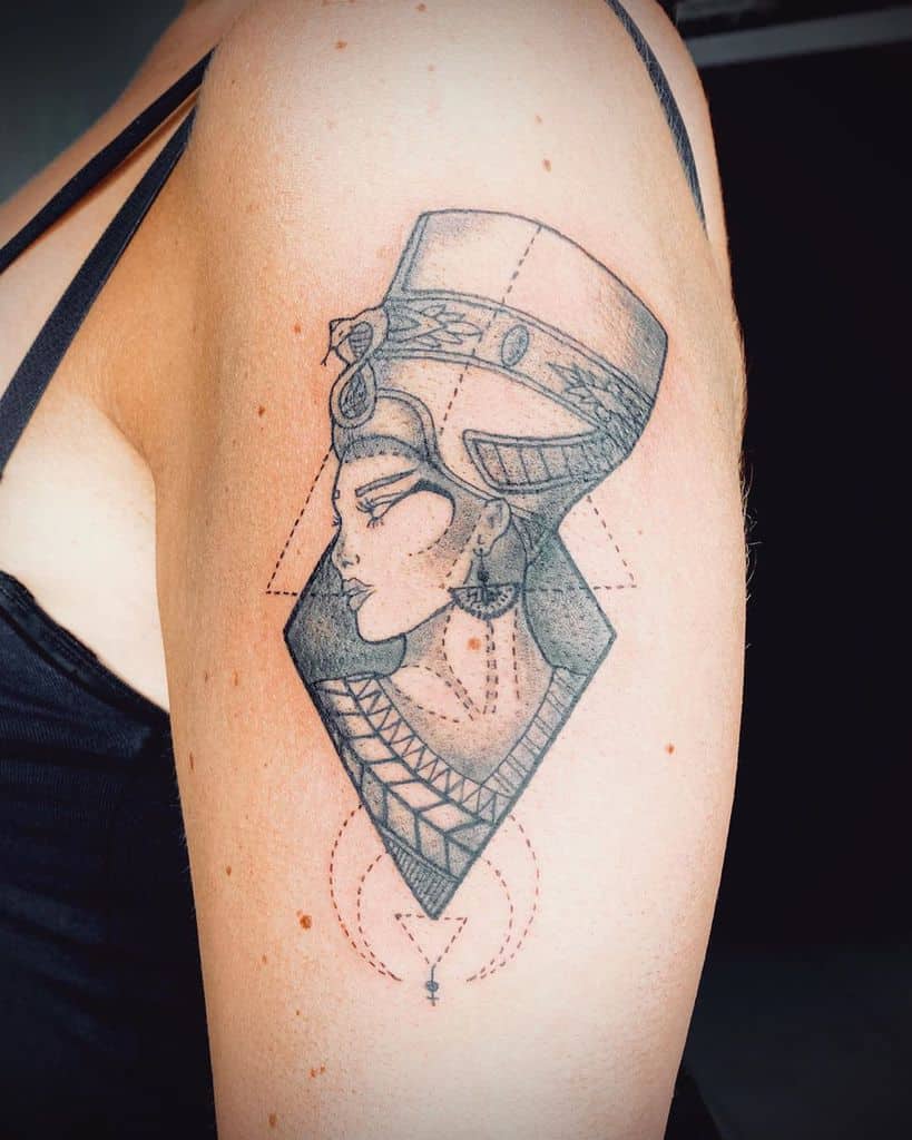 Tattoo of a stylized Nefertiti on an upper arm, featuring geometric shapes and detailed lines