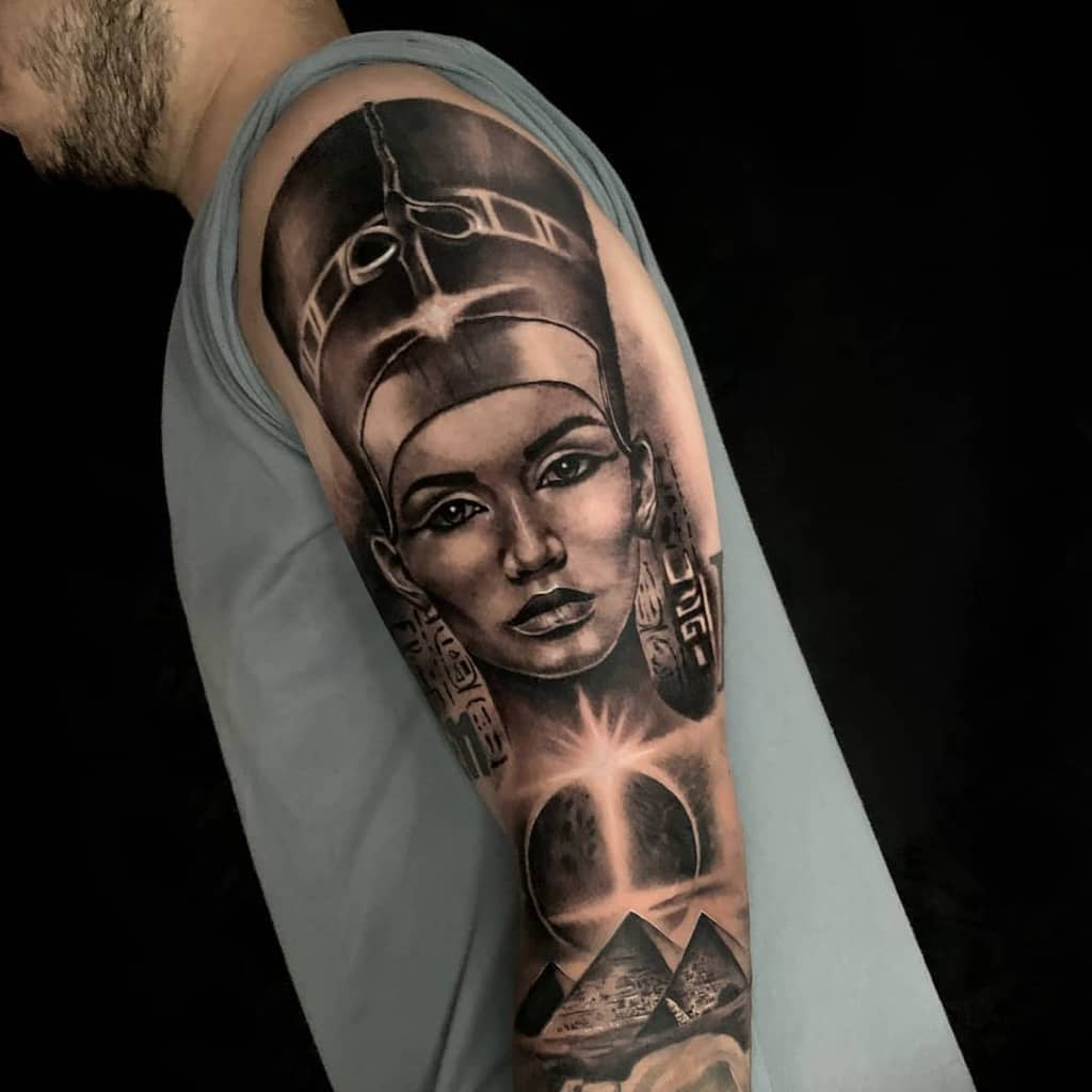 Full sleever arm tattoo featuring Queen Nefertiti, with pyramids and a radiant sun