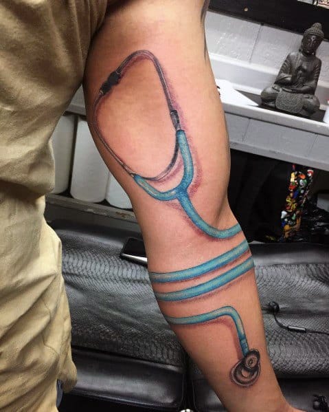 Blue stethoscope tattoo wrapping around the arm, creating a 3D effect that symbolizes a strong connection to the medical field.