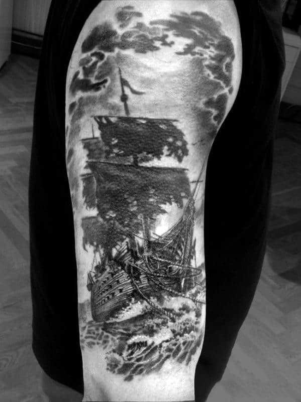 Black and white tattoo of a sailing ship in stormy seas on an upper arm
