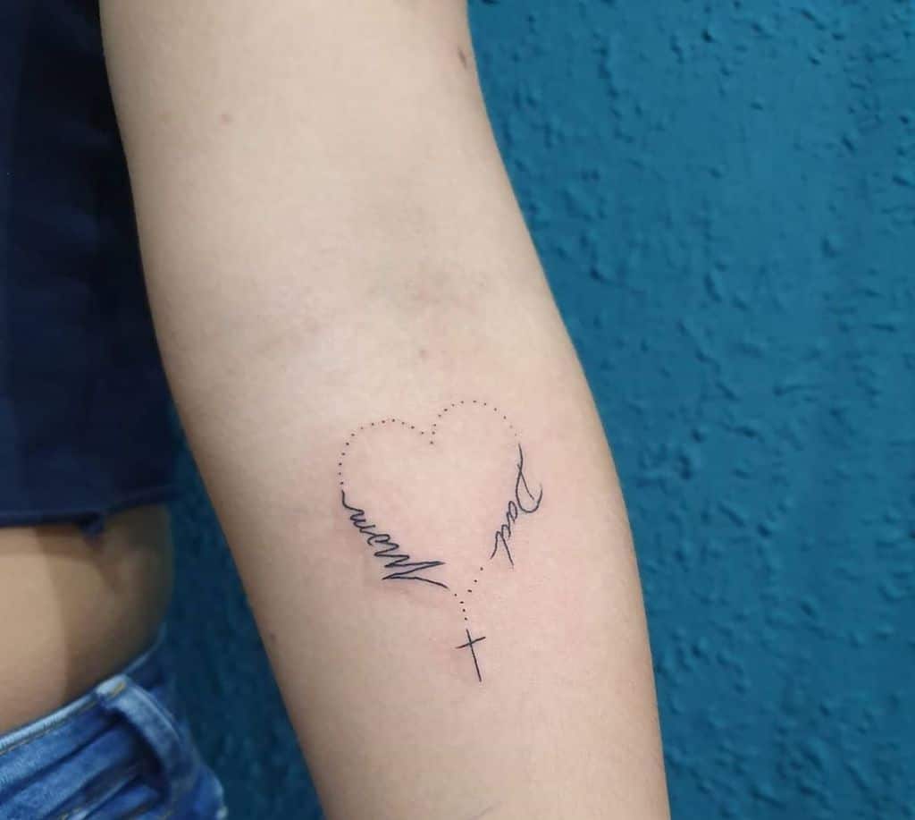 Minimalist tattoo of a heart outlined with dotted lines, with 'Mom' and 'Dad' written in cursive forming part of the shape, along with a small cross