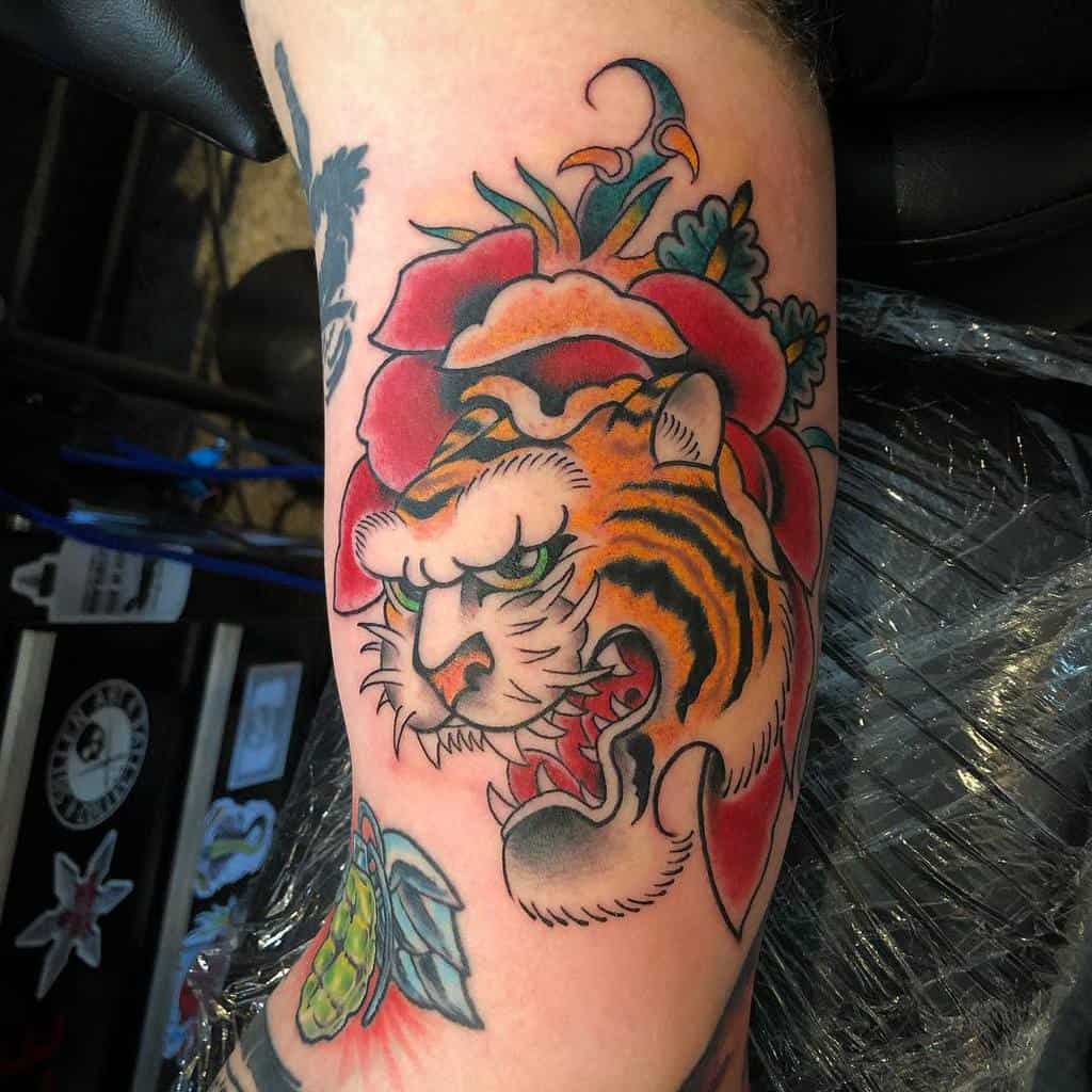 Colorful tattoo of a tiger's head with a floral design on an arm