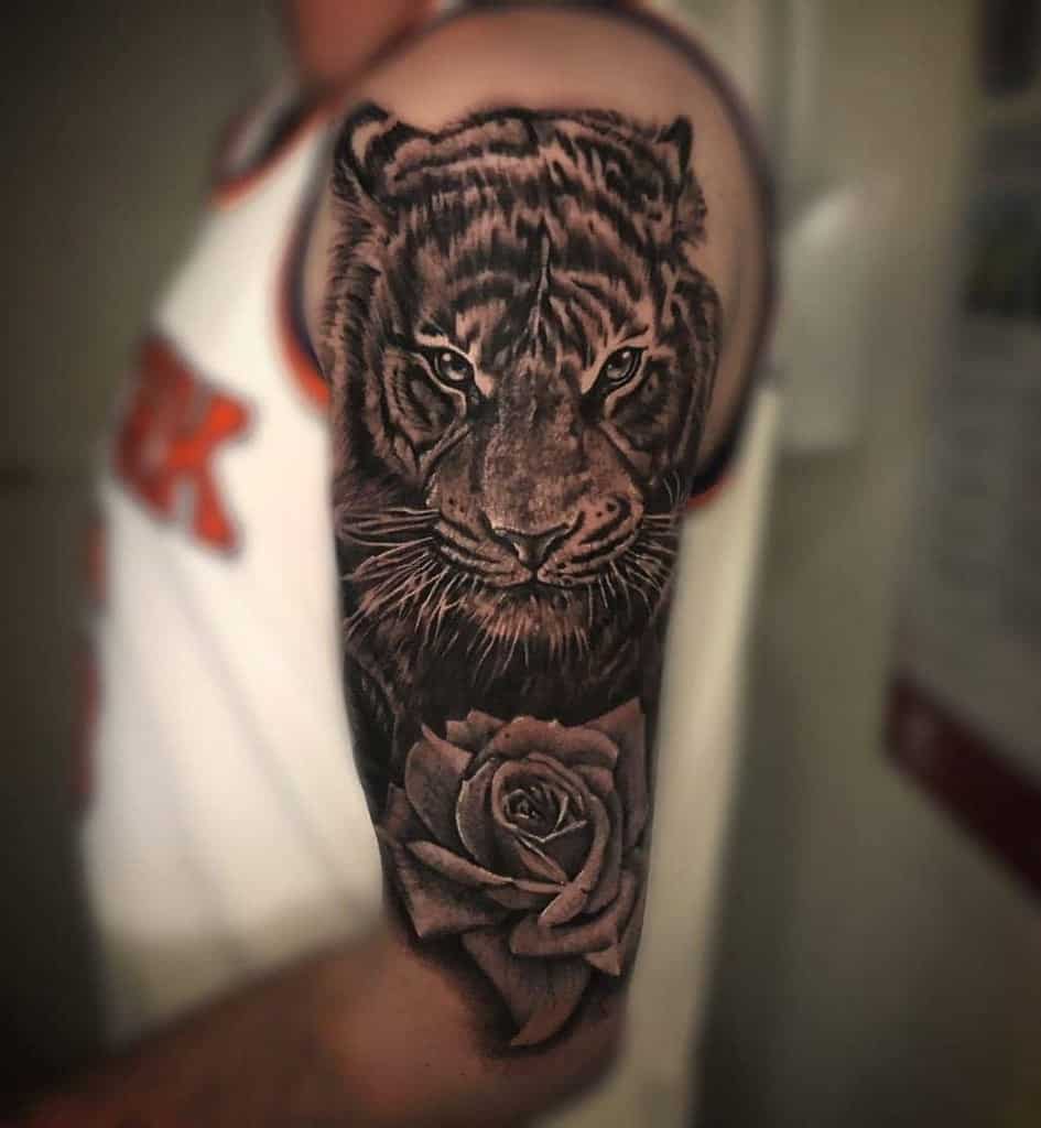 An upper arm tattoo featuring a striking tiger intertwined with a delicate rose