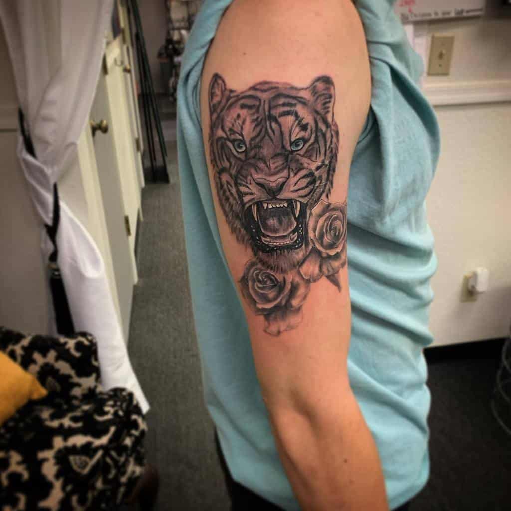 A striking tattoo of a roaring tiger intertwined with vibrant roses adorns the man's upper arm