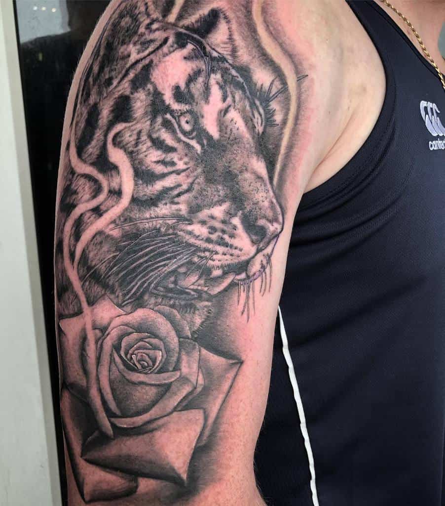 A striking tattoo of a majestic tiger intertwined with a delicate rose graces the man's upper arm