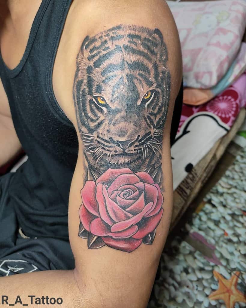 A striking tattoo of a fierce tiger intertwined with a delicate rose graces the upper arm
