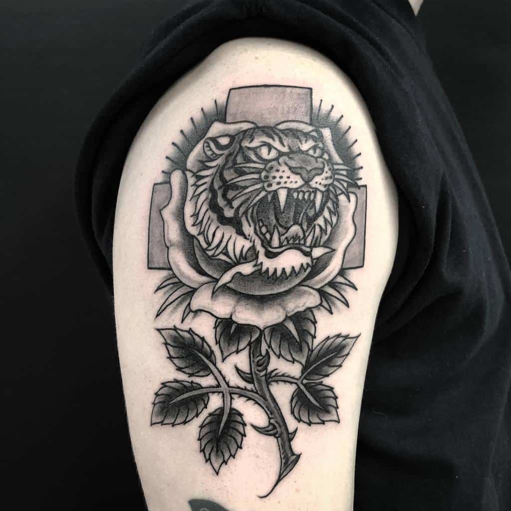 A stunning tattoo of a majestic tiger roaring fiercely, entwined with a beautifully detailed rose and its lush leaves, elegantly graces the upper arm