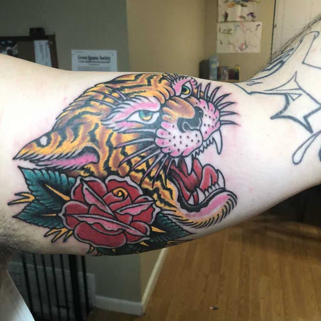 A vibrant tattoo of a roaring tiger head intertwined with a delicate rose graces the person's arm