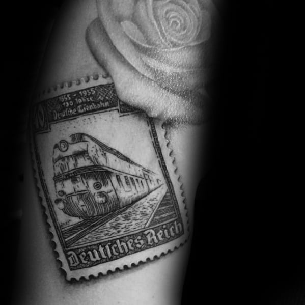 Tattoo of a postage stamp featuring a vintage train with a rose above it