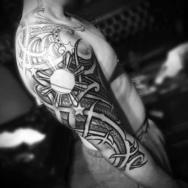 Filipino sun tattoo sleeve with bold tribal patterns, three stars, and intricate linework covering the shoulder and upper arm.