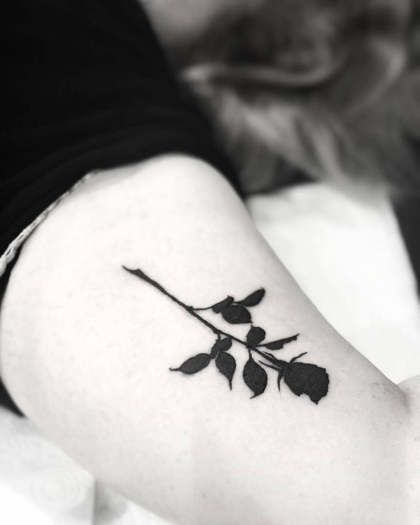 A tribal black rose tattoo elegantly adorns an arm