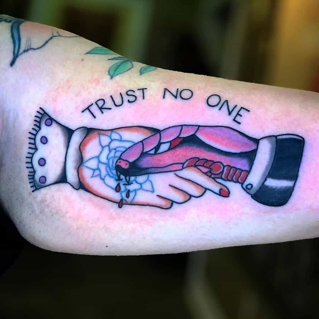 Tattoo of two shaking hands, one with a snake, blood drops, and text "Trust No One" above them