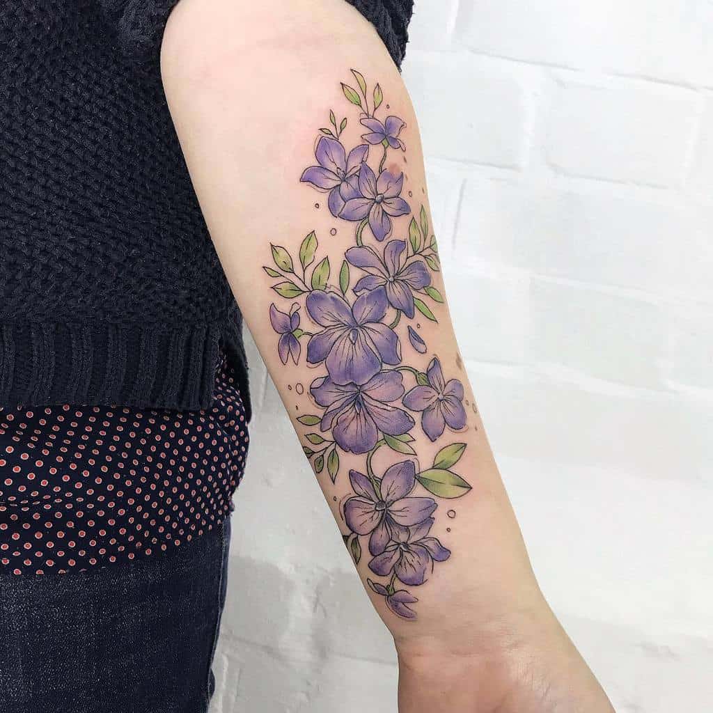 Vibrant violet flower tattoo, featuring delicate shading, green leaves, and a cascading floral design for a graceful, botanical look