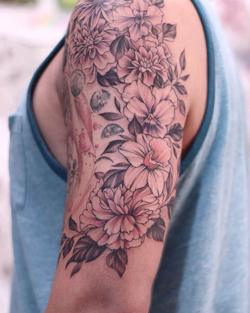 Elegant floral tattoo with intricate shading and soft pink hues, featuring detailed violet flower blossoms and leaves for a natural, artistic design