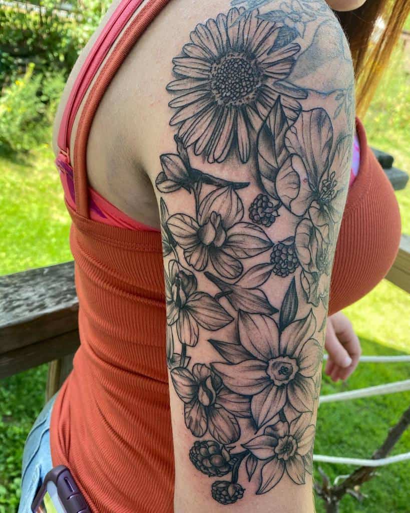 Detailed floral sleeve tattoo featuring sunflowers, daffodils, leaves, and berries in black ink, beautifully crafted on the arm