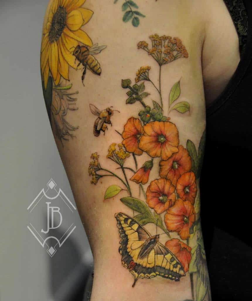 Arm tattoo with flowers, bees, a butterfly, and a sunflower