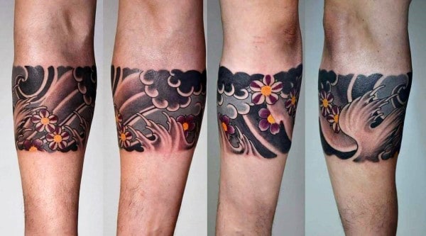 Japanese-style armband tattoo featuring bold black and grey waves with intricate cherry blossoms in shades of pink and yellow