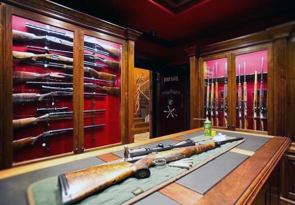 Luxury armory with wood and glass display cases, red velvet backing, and central workbench.
