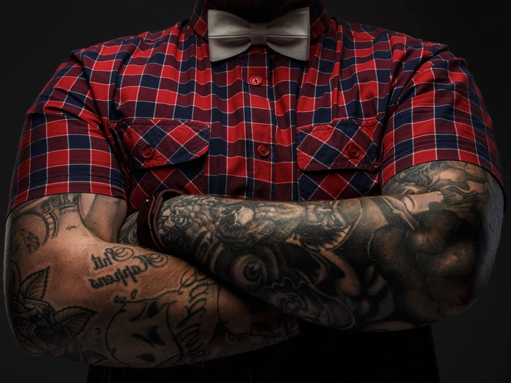 A pair of man's crossed arms that are covered in tattoos